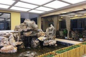 Un hall d’hôtel agrémenté d’un jardin de rochers et d’un espace salon.