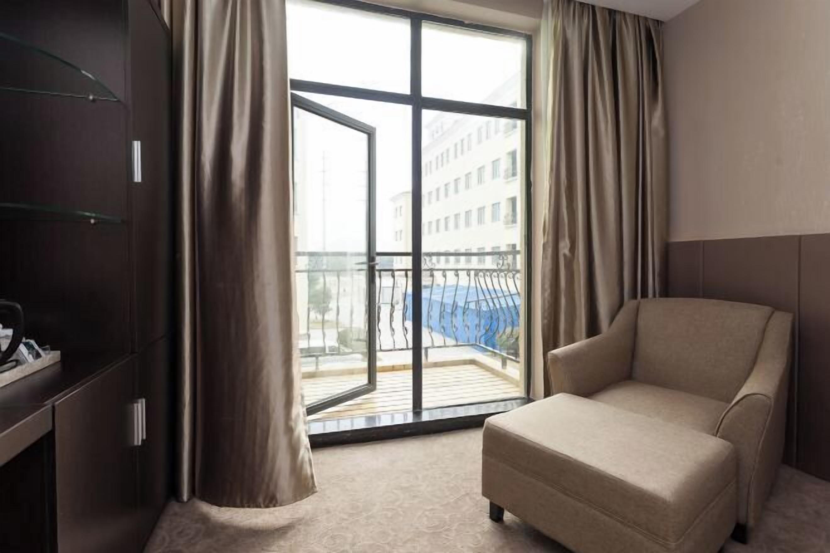 Une chambre d’hôtel avec une grande fenêtre, un canapé et un bureau avec un téléphone.