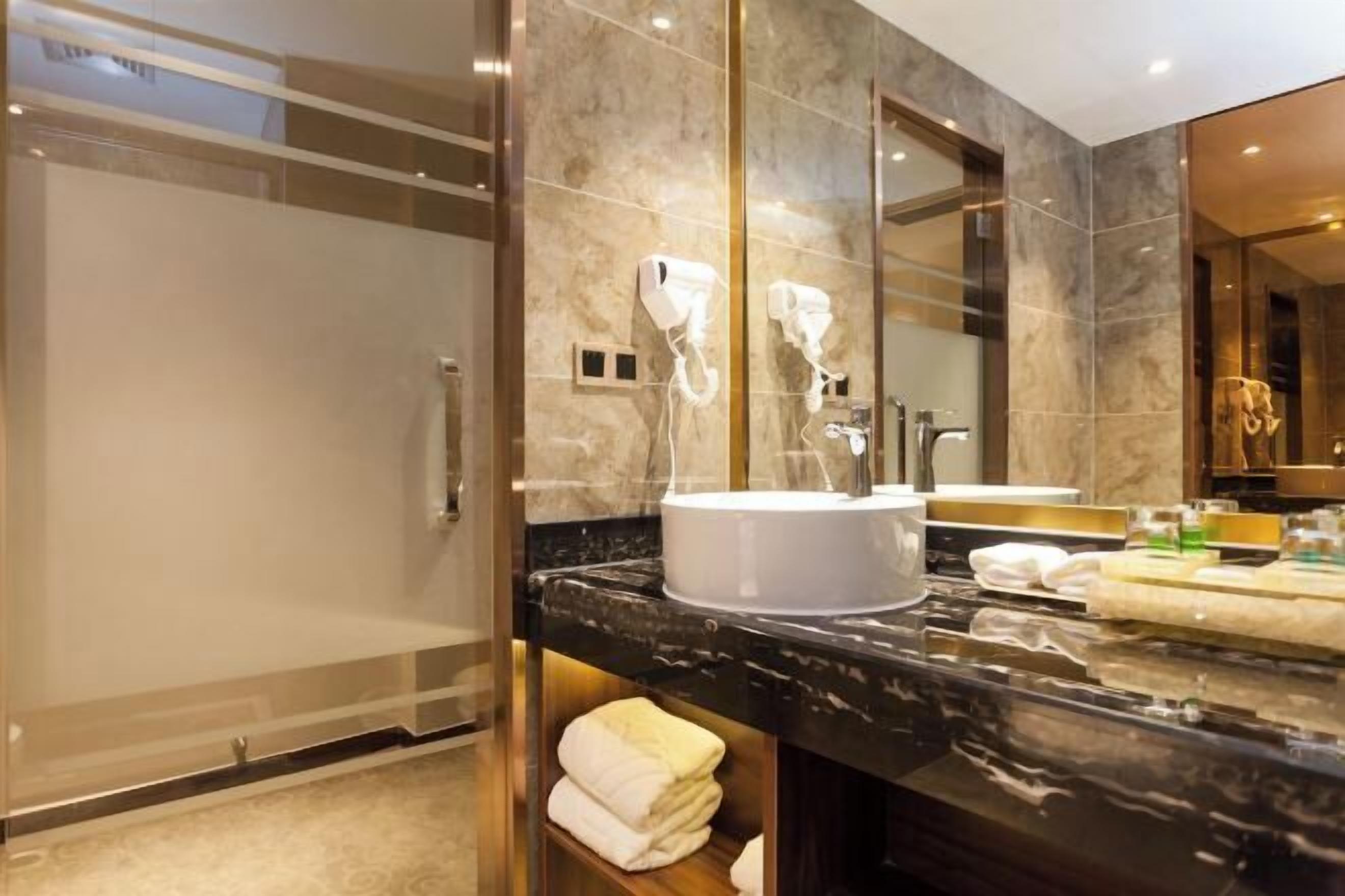 A modern bathroom with a glass-enclosed shower, a marble countertop, and a large mirror.