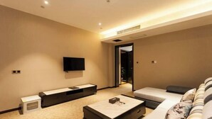 Una habitación de hotel moderna con un televisor de pantalla plana montado en la pared, un sofá, una mesa de centro y una mesita de noche.