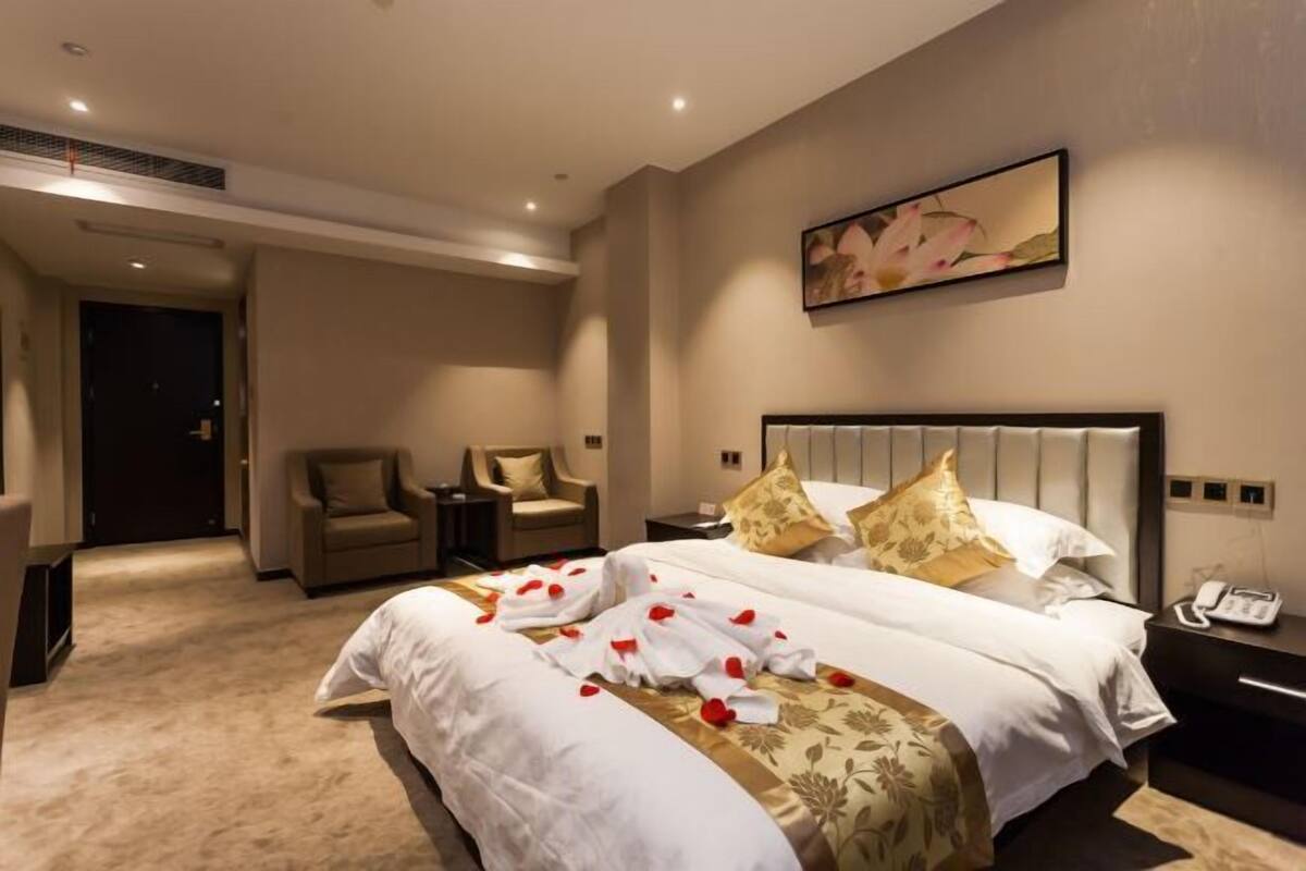 A hotel room with a large bed, two bedside tables, a chair, and a painting on the wall.