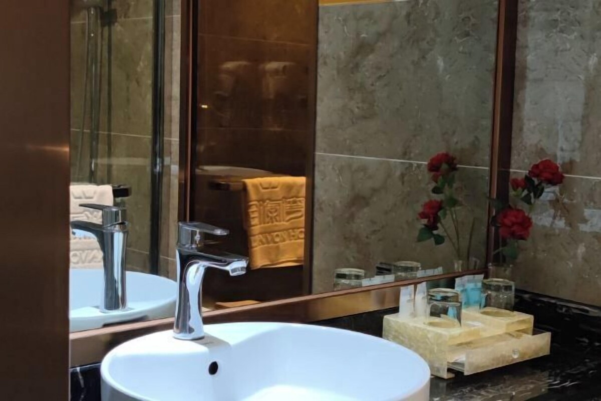 Une salle de bain avec un lavabo blanc, des robinets chromés, un grand miroir et un porte-serviettes.