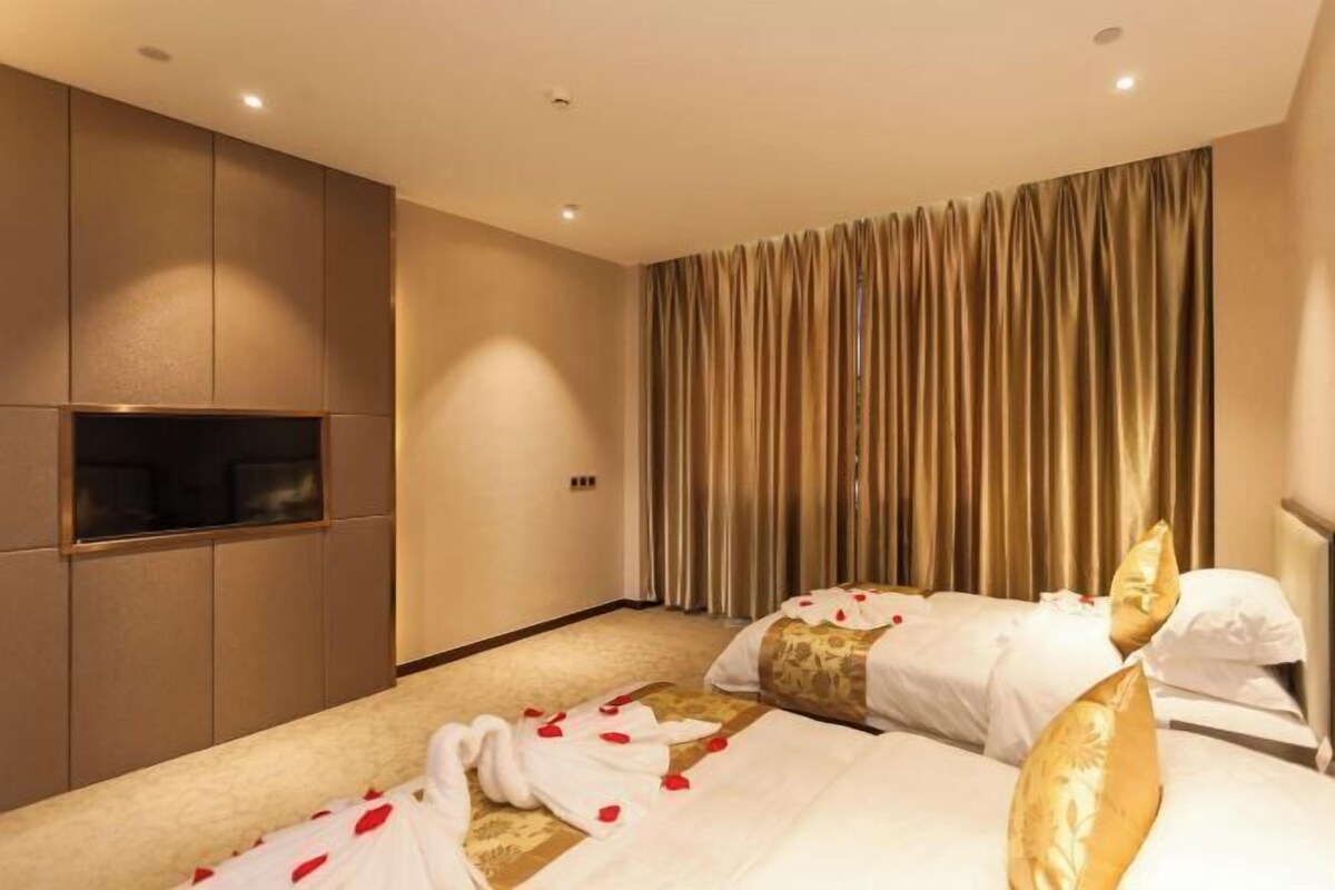 Une chambre d’hôtel avec deux lits, un minibar et une grande fenêtre avec des rideaux.