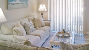 A living room with a sofa, a coffee table, a lamp, and a painting on the wall.