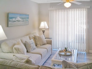 A living room with a sofa, a coffee table, a lamp, and a painting on the wall.