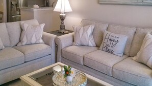A living room with two sofas, a coffee table with a decorative tray, a lamp, and a painting on the wall.