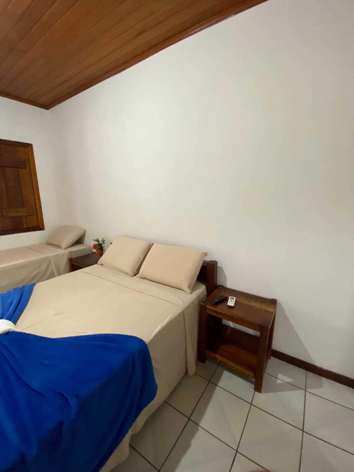Une chambre à coucher comprenant un lit, une table de chevet, une tête de lit en bois et une fenêtre avec un cadre en bois.