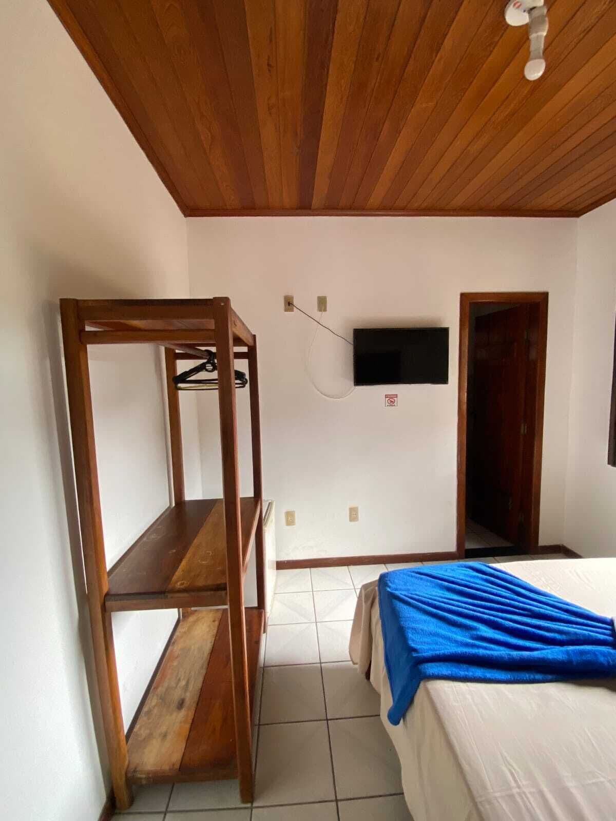 A bedroom with a bunk bed, a TV mounted on the wall, and a wooden ceiling.