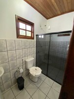 Un baño con inodoro, cabina de ducha y ventana.