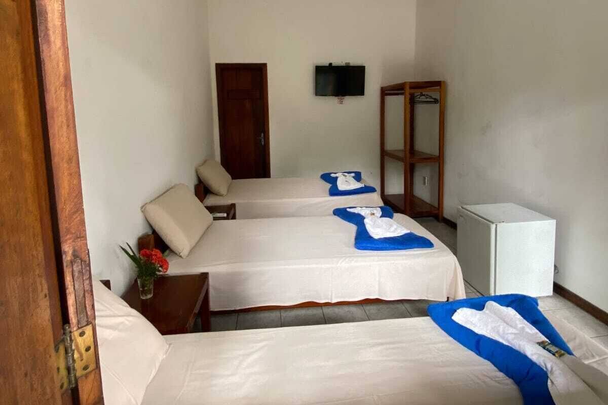 A hotel room with two beds, a TV, a wardrobe, and a small refrigerator.