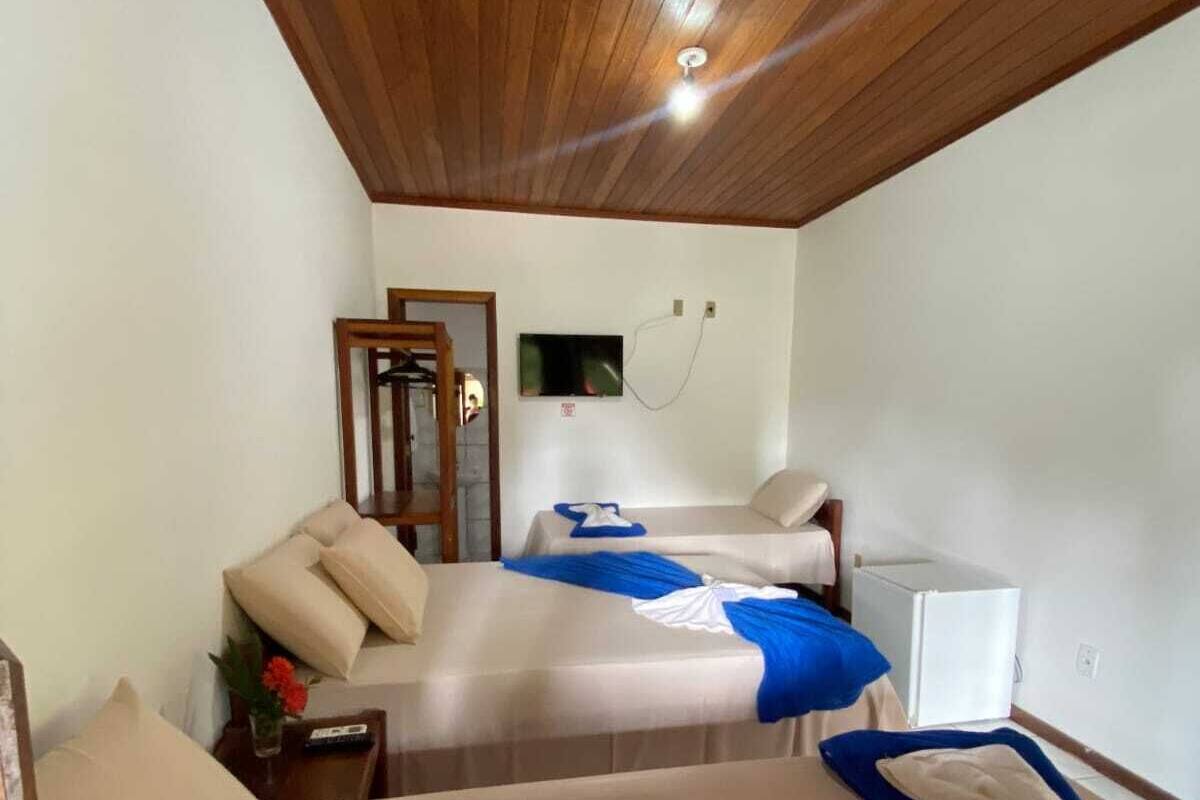 A room with two beds, a television, and a small white refrigerator.
