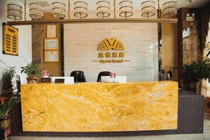 Un mostrador de recepción con encimera de mármol, un logotipo encima y un letrero que indica la zona de recepción.