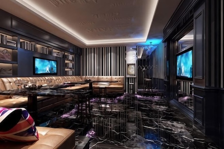 A modern living room with a sectional sofa, a flat-screen TV, a marble floor, and a bookshelf.. Beiliu Hyatt Hotel