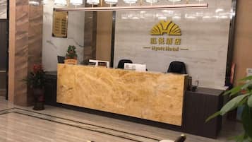 Un mostrador de recepción de hotel con encimera de mármol, una zona de recepción y un escritorio con una silla.
