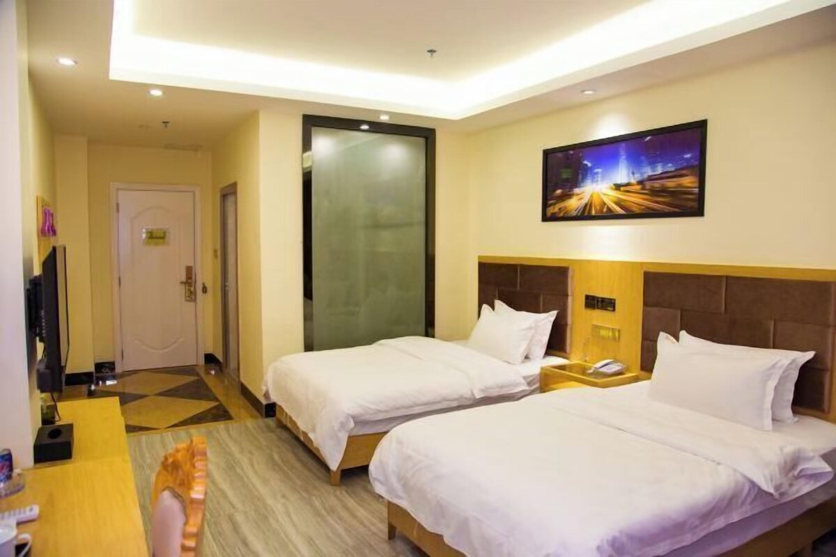 A hotel room with two beds, a television, and a painting on the wall.