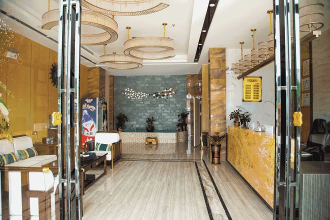 Un vestíbulo de hotel con mostrador de recepción, zona de estar y una pared decorativa.