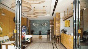 A hotel lobby with a marble floor, a reception desk, and a seating area with sofas and a coffee table. - Beiliu Hyatt Hotel (Beiliu)
