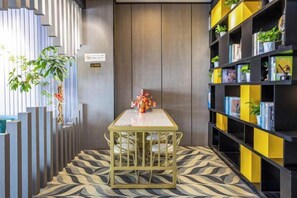 A room with a patterned floor, a table with chairs, a bookshelf with books and plants, and a vertical garden. - GYA Hotell(Jingjiang gongsuoqiao store&Jiangyin Industrial Park ) (Jingjiang)