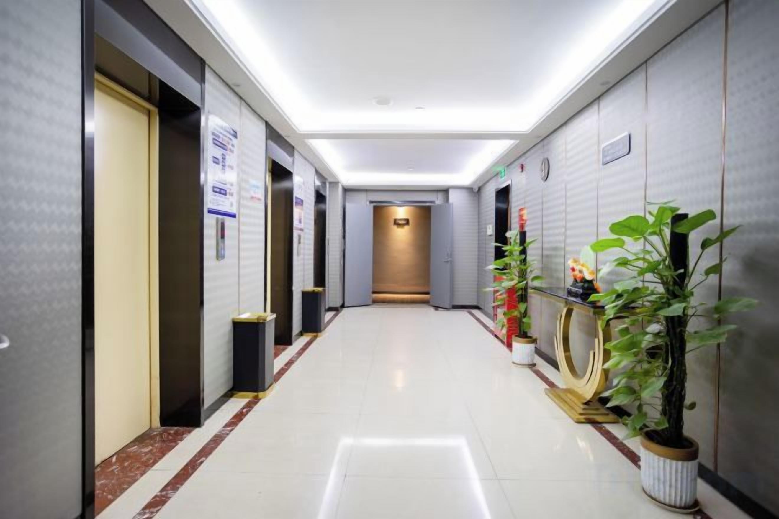 Un pasillo de hotel con puertas, un cubo de basura y plantas en macetas.