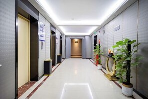 A hotel corridor with doors, a trash bin, and potted plants. - GYA Hotell(Jingjiang gongsuoqiao store&Jiangyin Industrial Park ) (Jingjiang)