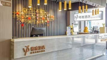 Un comptoir d’accueil d’hôtel au design moderne, doté d’un écran numérique et d’une enseigne indiquant le nom de l’hôtel.