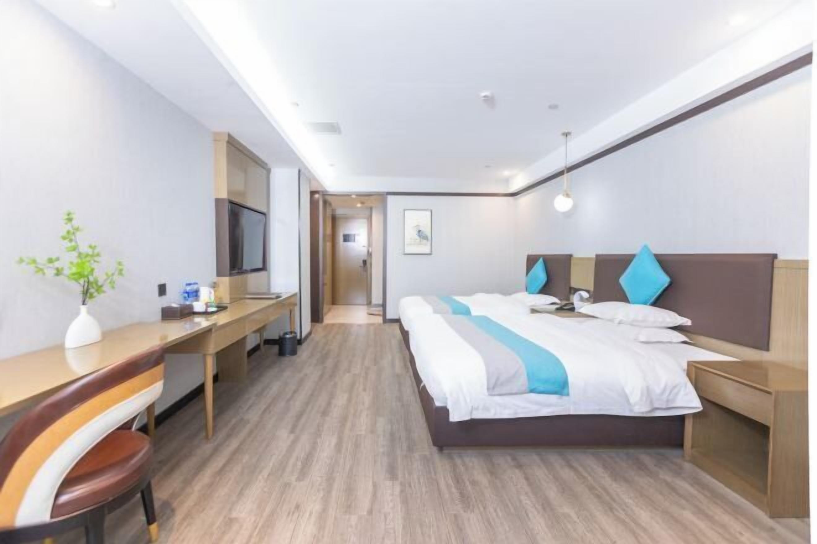 A hotel room with a bed, desk, chair, and a TV.