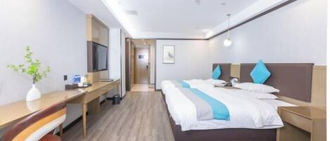 A hotel room with a bed, desk, chair, and a TV.