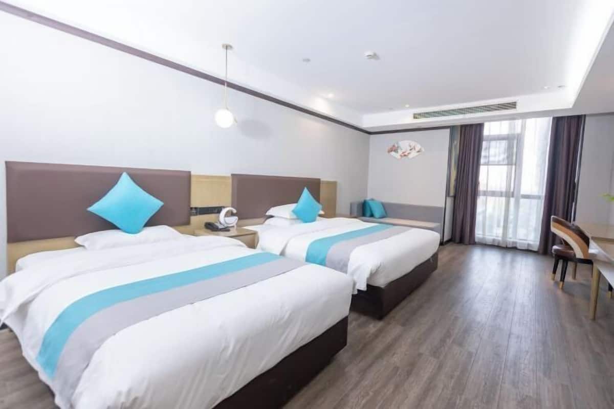 A hotel room with two beds, a desk, and a chair.