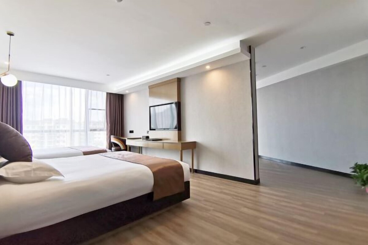 Una camera d'albergo moderna con un letto grande, una scrivania, una TV e una grande finestra.