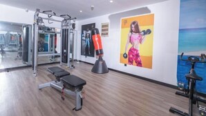 A gym with exercise equipment, a bench, a punching bag, and a painting of a woman. - GYA Hotell(Jingjiang gongsuoqiao store&Jiangyin Industrial Park ) (Jingjiang)