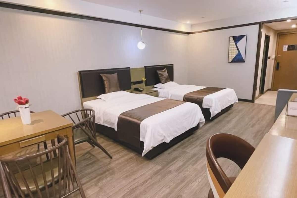 A hotel room with two beds, a desk, and a chair.