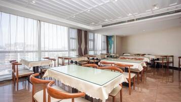 A spacious dining area with multiple tables and chairs, large windows, and a high ceiling.