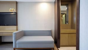 Un salon moderne avec un canapé gris clair, des meubles en bois et un téléviseur à écran plat fixé au mur.