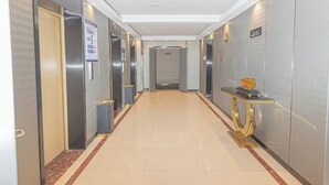 A hotel corridor with elevators, a reception desk, and a trash bin. - GYA Hotell(Jingjiang gongsuoqiao store&Jiangyin Industrial Park ) (Jingjiang)
