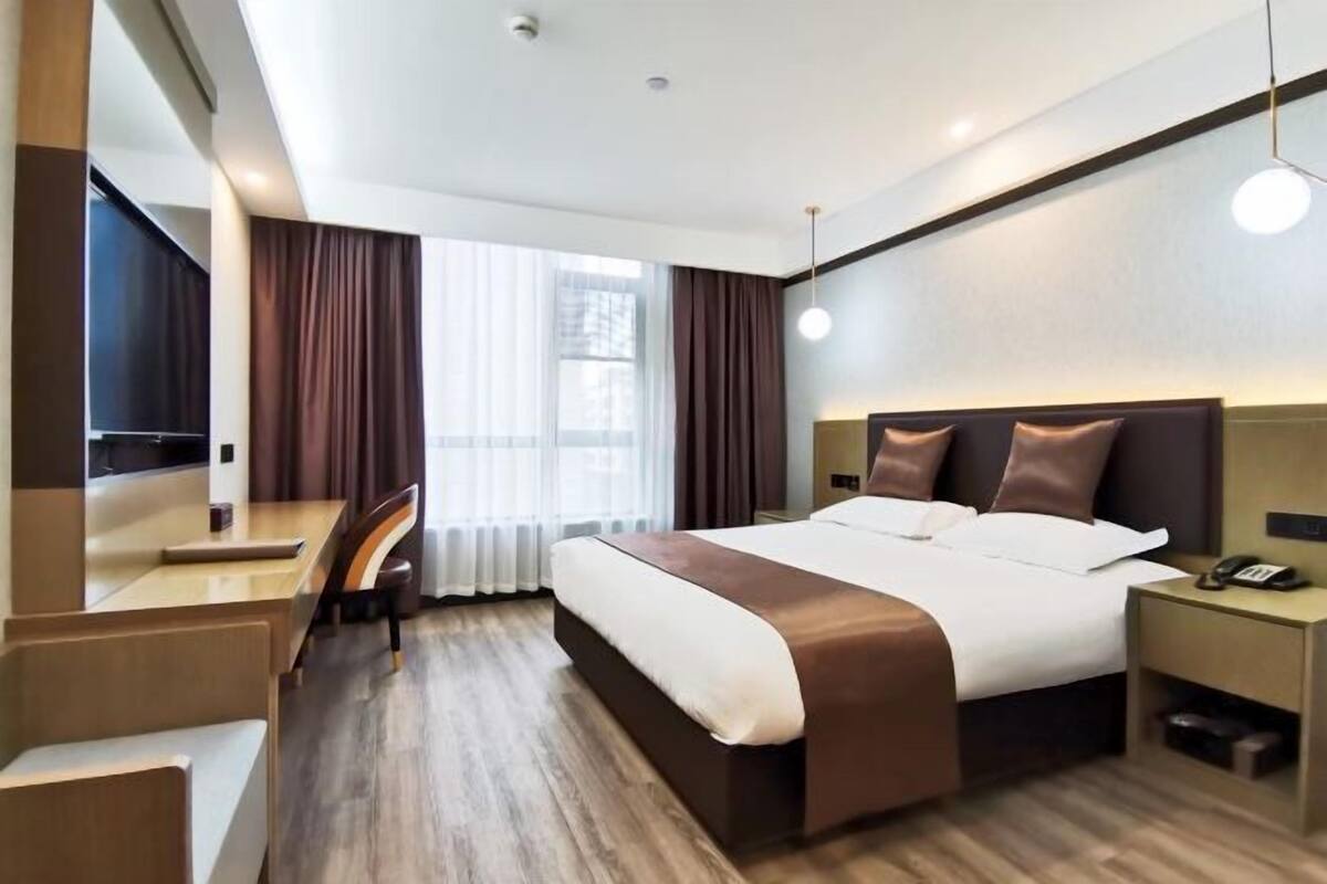 A modern hotel room with a large bed, a desk, and a chair.