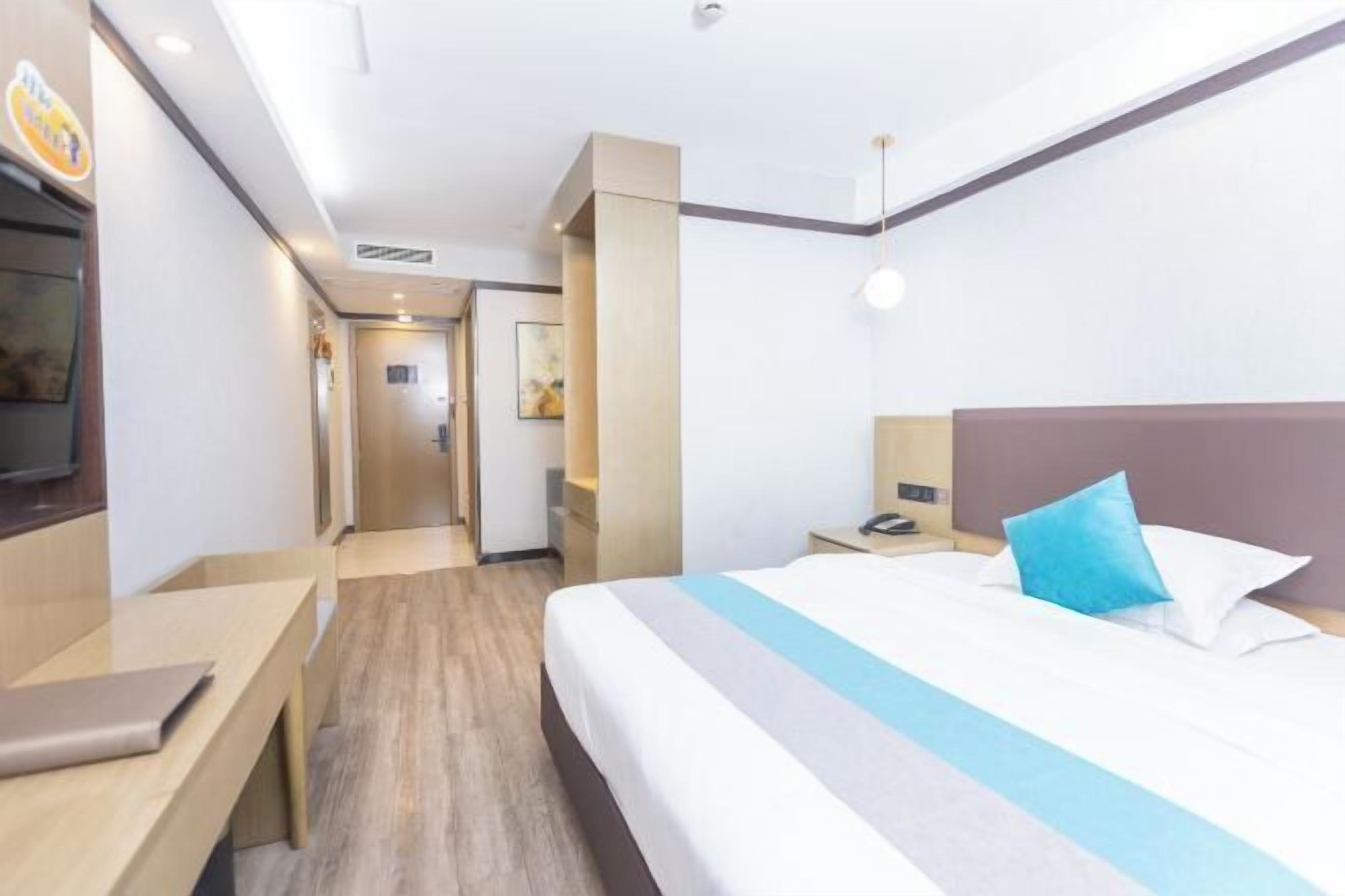 Una habitación de hotel con cama, mesita de noche y escritorio con una computadora portátil.