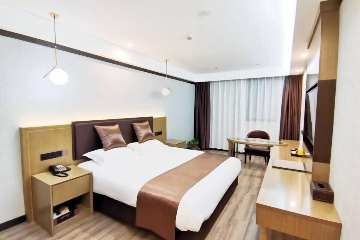 A hotel room with a large bed, bedside tables, a desk, and a chair.