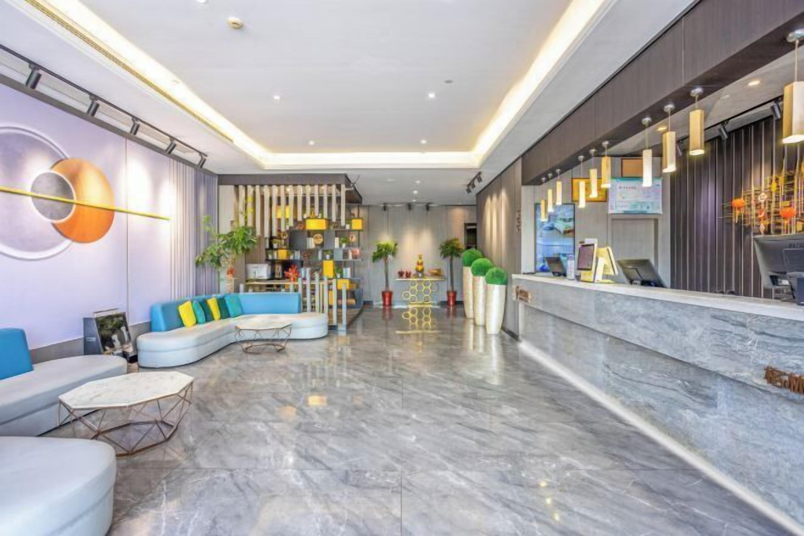 Un lobby moderno de hotel con una zona de estar curva, un mostrador de recepción y una pared decorativa.