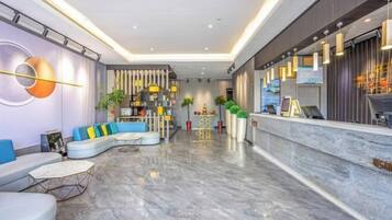 Un lobby moderno de hotel con una zona de estar curva, un mostrador de recepción y una pared decorativa.