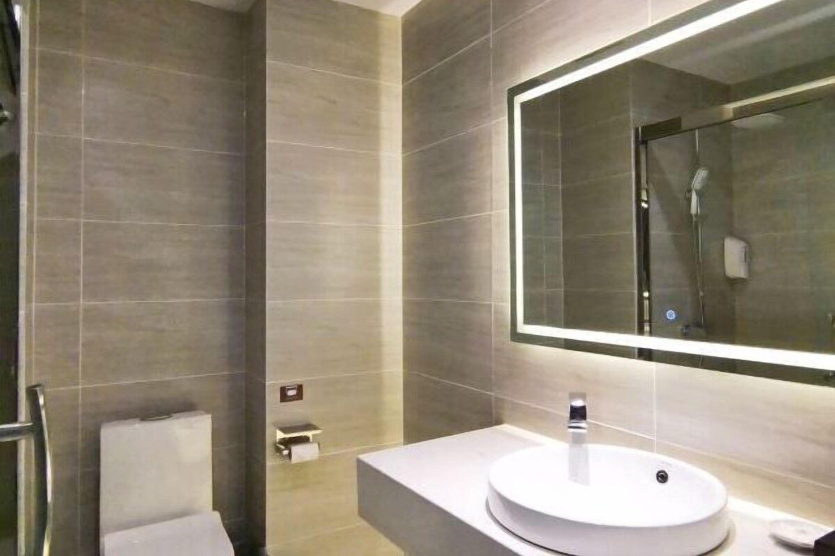 Un bagno moderno con un grande specchio, un lavabo rotondo e un box doccia in vetro.