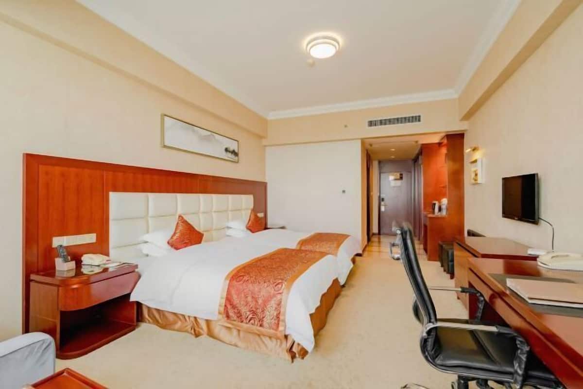 Une chambre d’hôtel avec un grand lit, un bureau, une chaise et un téléviseur.