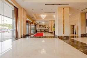 Eine Hotellobby mit Marmorboden, rotem Teppich und einer Rezeption.