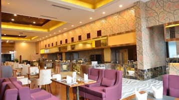 Un vestíbulo de hotel con zona de bar, arreglos de asientos y un muro estampado.