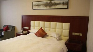 Une chambre d’hôtel avec un grand lit, une tête de lit, une table de chevet, une chaise et un tableau au mur.