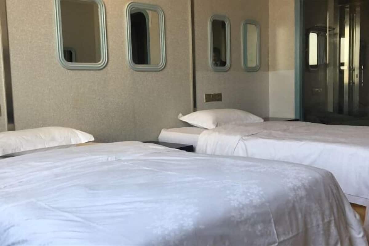 Une chambre d’hôtel avec deux lits, un grand miroir et une porte coulissante donnant accès à la salle de bain.
