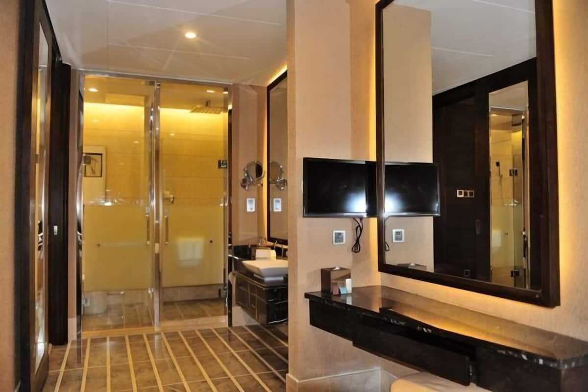 A modern bathroom with a large mirror, a shower, and a vanity with a sink.