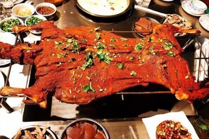 Un cerdo asado al girar, rodeado de diversos platos y condimentos.