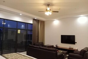 Una sala de estar moderna con un sofá grande, una mesa de centro y un televisor de pantalla plana montado en la pared.