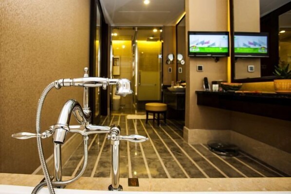 Un baño moderno con cabezal de ducha cromado, un lavamanos y un televisor montado en la pared.