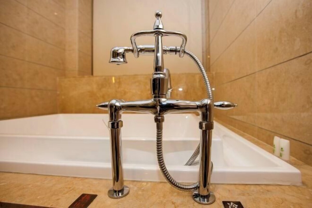 A modern bathroom with a chrome faucet, a handheld showerhead, and a bathtub.